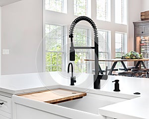 A black faucet on a white farmhouse sink.