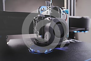 black FDM 3D printer manufactures a hollow part from metallic blue plastic in thick layers