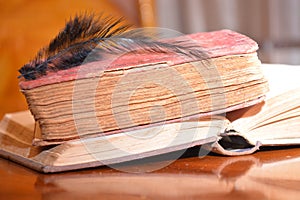 Black feather on old books on wood table reading for university school education