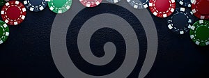 A black felt surface with poker chips scattered around the outside edge of the frame. On a dark black background. T