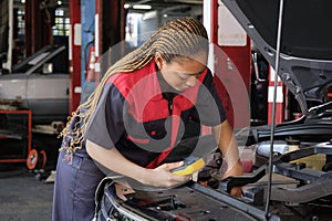 A black female automotive mechanical worker checks EV car at a fixing garage.