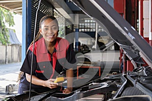 A black female automotive mechanical worker checks EV car at a fixing garage.