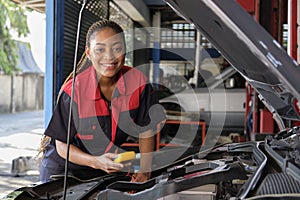 A black female automotive mechanical worker checks EV car at a fixing garage.