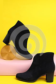 Black female boots and decor on yellow background