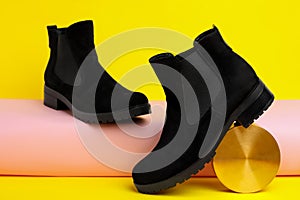 Black female boots and decor on yellow background