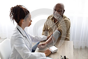 Black female doctor checking measuring pressure on patient& x27;s hand