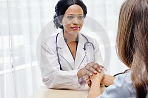 Black female doctor holding hands young woman patient with love, care, helping, encourage and empathy at hospital