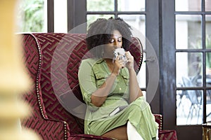 Black Female Drinking a Cup of Coffee or CBD Tea in a Living Room