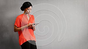 Black female entrepreneur busy using a tablet against textured wall