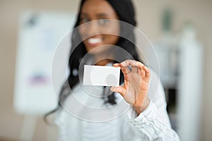 Black female entrepreneur holding empty business card at company office, mockup for design