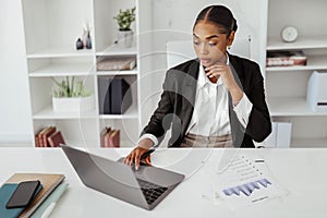 Black female entrepreneur working with laptop and papers at workplace in office, managing financial reports, copy space