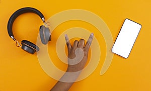 Black female hand making rock gesture between headphones and smartphone