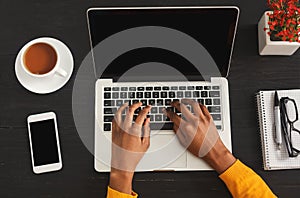 Black female hands typing on laptop keyboard, top view photo