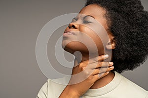 Black female holding hand at neck because of pain, sore throat, uncomfortable feeling at swallowing