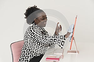 Black female office worker cleaning computer screen. Smiling woman.