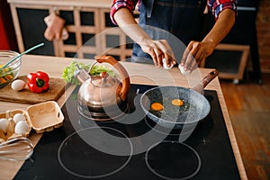 Black female person cooking fried eggs on kitchen