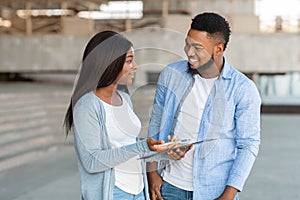 Black female volunteer conducting survey with young man on the street