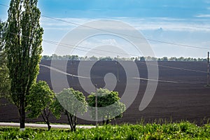 Black fertile soil on a sprinkled spring field. Landscape