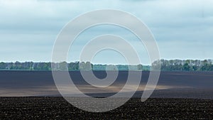 Black fertile soil on a sprinkled spring field. Landscape