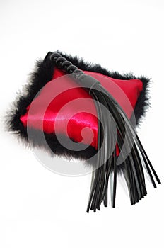 Black fetish flogging whip and on red pillow photo
