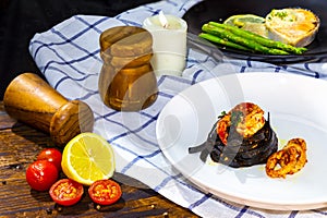 Black fettuccine spaghetti pasta with rock shrimp and squid topping with green parsley; Salmon steak with green asparagus on wood