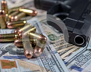 Black firearm and bullets  close-up on a pile of United States currency.