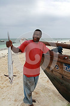 Black fisherman from the island of Zanzibar holding mackerel