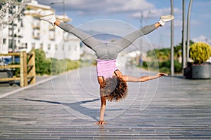 Black fit woman doing fitness acrobatics in urban background photo