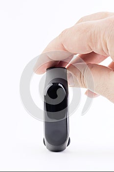 Black fitness bracelet in a female hand isolated on a white background. The concept of modern gadgets for sports and healthcare.