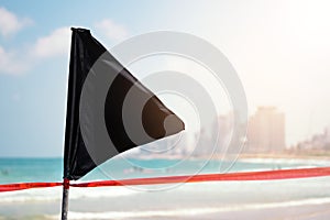 Black flag on the sea shore warning about dangerous current and waves or invasion of jellyfish
