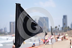 Black flag on the sea shore warning about dangerous current and waves or invasion of jellyfish