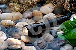 A black flashlight in a small stream