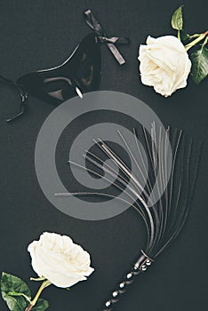 Black flogging whip and mask with white roses photo