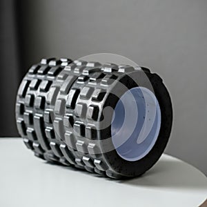 Black foam roller with a textured grid pattern, designed for exercise and muscle