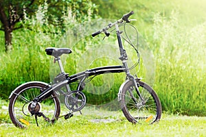 Black folding bicycle in grass