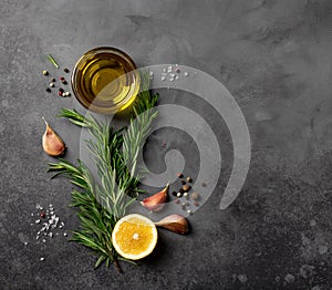 Black food background with olive oil, rosemary, lemon and spices.