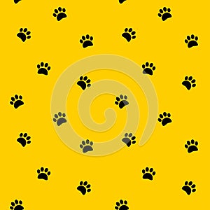 Black footprints paws vector seamless pattern on yellow background