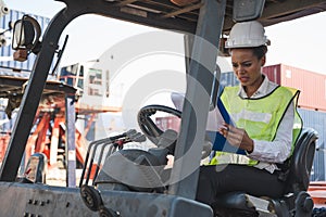 Black foreman woman worker driving forklift checking at Container cargo harbor to loading containers and has a problem. African