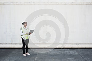 Black foreman woman worker working checking at Container cargo harbor holding laptop computer to loading containers. African dock