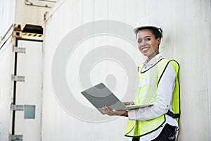 Black foreman woman worker working checking at Container cargo harbor holding laptop computer to loading containers. African dock