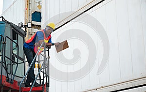 Black foreman worker working control the crane and forklift at Container cargo harbor to loading containers. African dock male