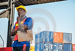 Black foreman worker working control the crane and forklift at Container cargo harbor to loading containers. African dock male