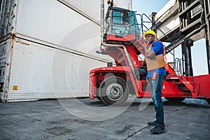 Black foreman worker working control the crane and forklift at Container cargo harbor to loading containers. African dock male