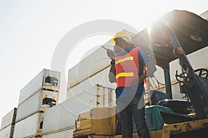 Black foreman worker working control the crane and forklift at Container cargo harbor to loading containers. African dock male