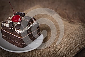 Black Forest Cake topping cherry putting on the white plate on the Sack Bags and wood table background
