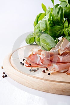 Black forest ham and basil on wooden cutting board
