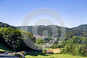 Black Forest high road with view to landscape in the Black Forest with houses on green hills and fir-covered mountains.