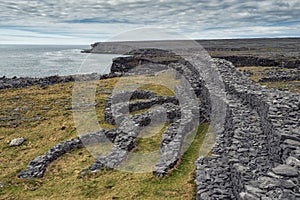 Black fort and rough stone coast line of Aran islands, county Galway, Ireland. Popular landmark. Travel and tourism. Cloudy sky.