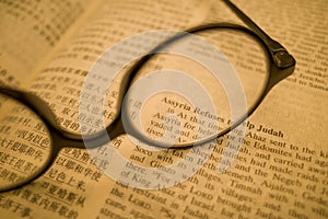 Black frame glasses are placed on the Chinese-English Bible
