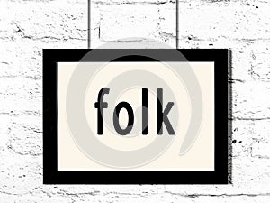 Black frame hanging on white brick wall with inscription folk